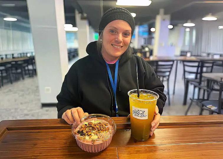 Student smiling at counter with beverage and acai bowl