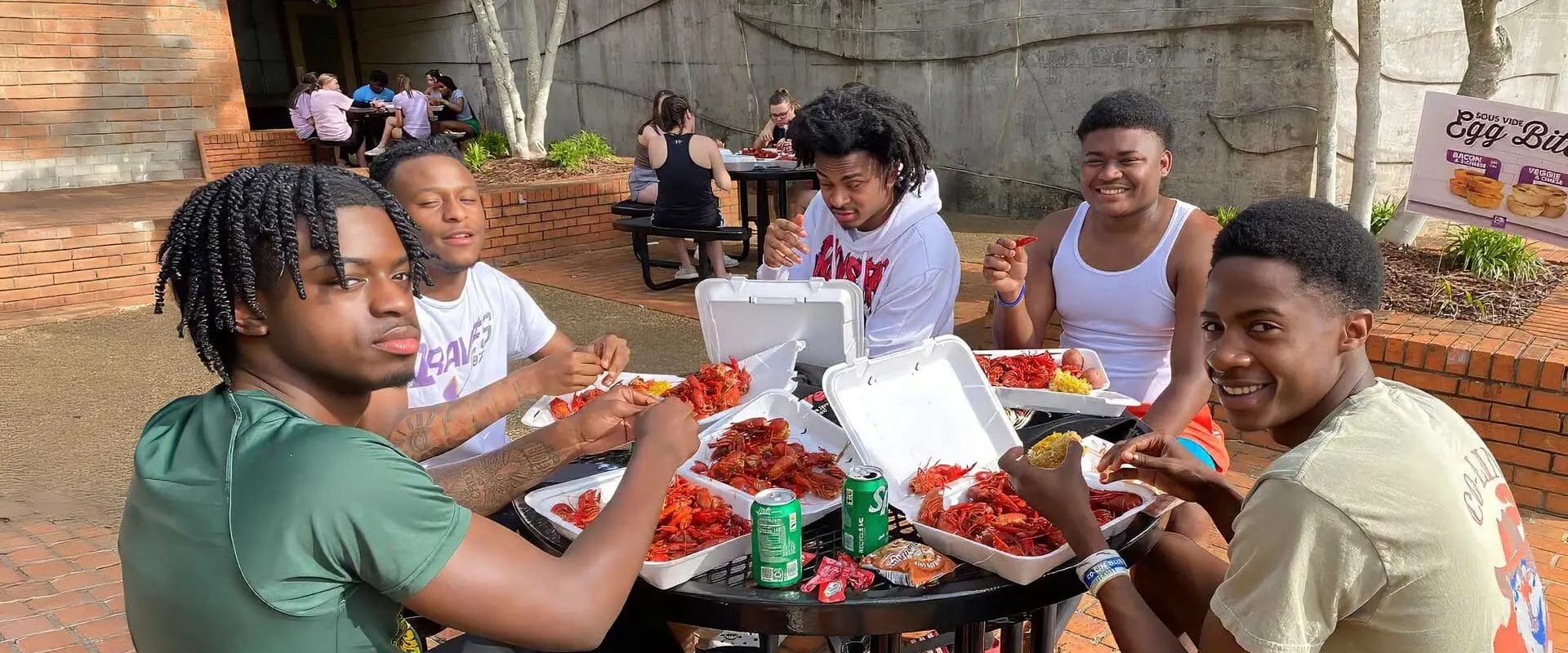 Students sitting outside enjoying a crawfish boil