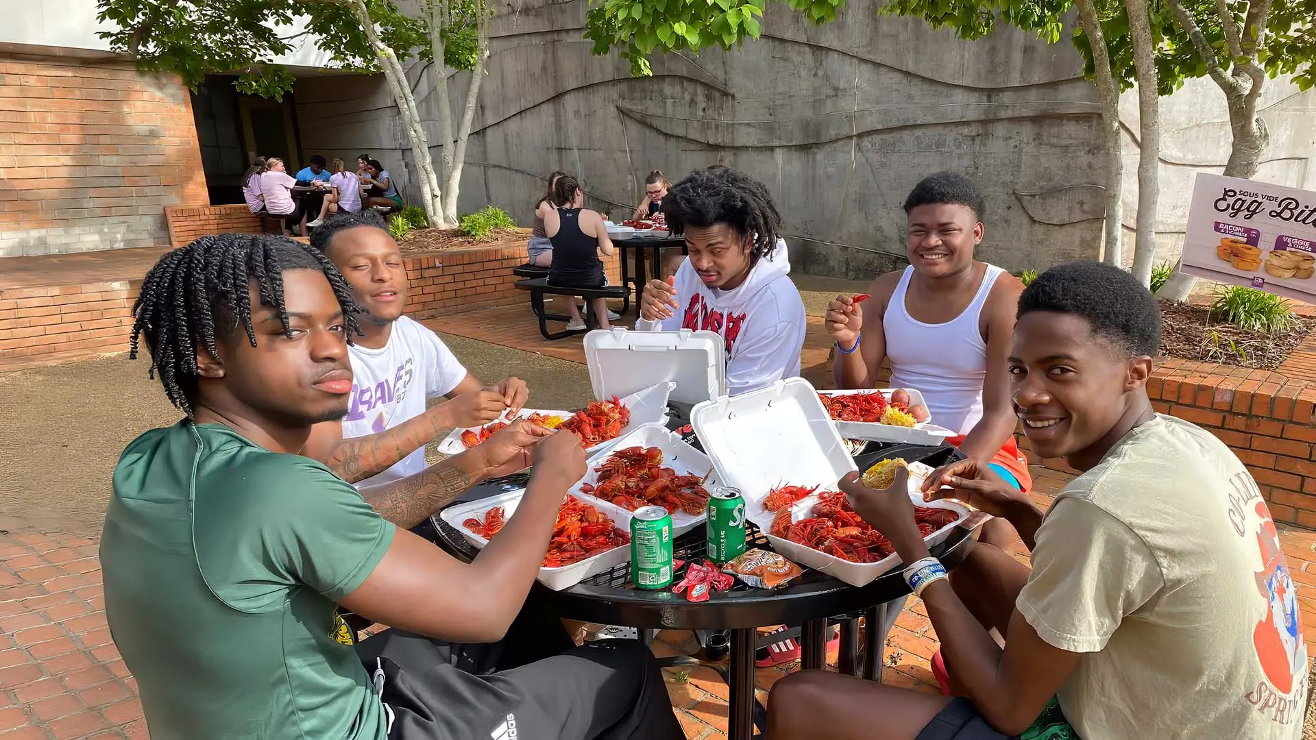 Students sitting outside enjoying a crawfish boil